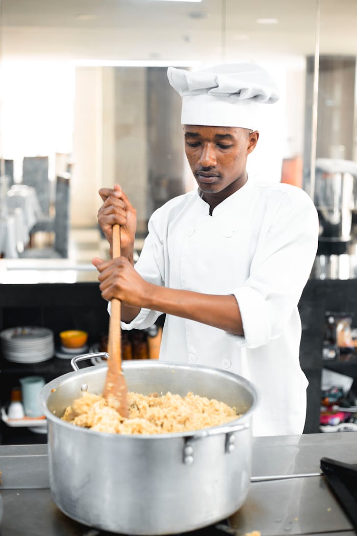 professional-chef-stirring-large-pot-in-modern-kitchen-32985388