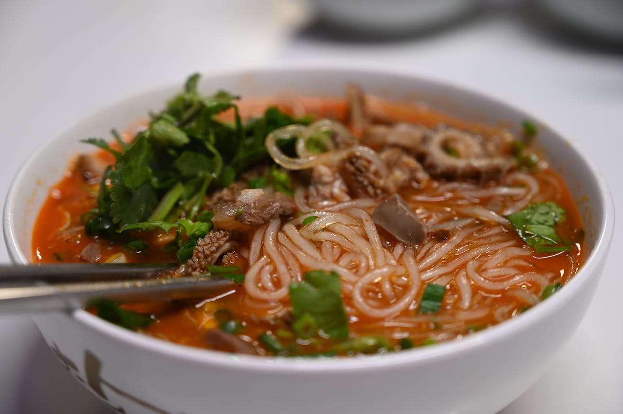 Close-up of a flavorful spicy noodle soup garnished with fresh cilantro and tripe.
